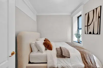 a white bedroom with a bed and a chair at Modern 3BR in Gramercy -Near Union Sq NYU in New York