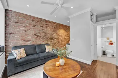 a living room with a couch and a brick wall at Modern 3BR in Gramercy -Near Union Sq NYU in New York