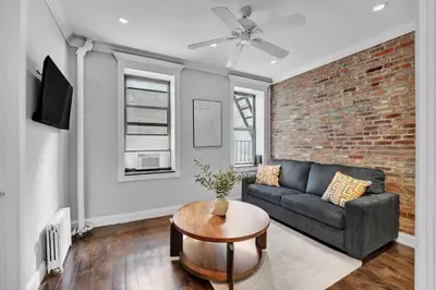 a living room with a couch and a brick wall at Modern 3BR in Gramercy -Near Union Sq NYU in New York