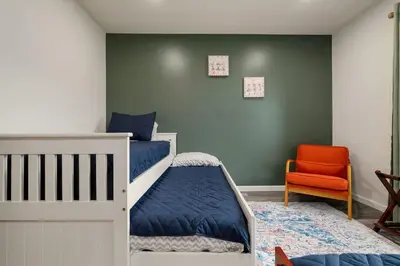 a bedroom with two bunk beds and an orange chair at Upstate NY Escape - Game Ready, Game Room, Pool Table, Firepit, Delaware River in Sparrow Bush