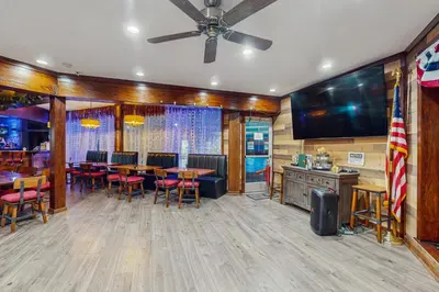 a bar with tables and chairs and a large screen at Lounging in Long Pond in Long Pond
