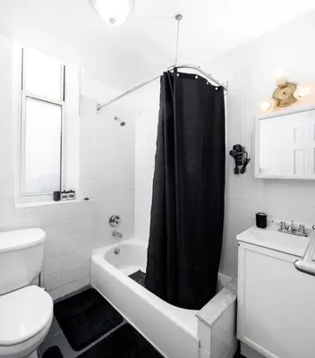 a bathroom with a black shower curtain and a toilet at Studio in New York in Brooklyn