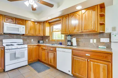 a kitchen with wooden cabinets and white appliances at Home Theater and Game Room Home in Glen Wild! in Glen Wild