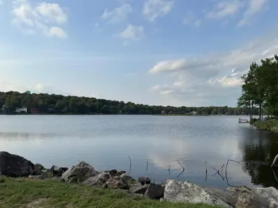 a large body of water with rocks and trees at Lovely tranquil spot for family and friends to gather in Tobyhanna
