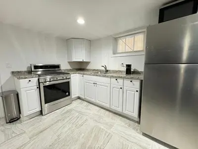 a kitchen with white cabinets and a stainless steel refrigerator at Open Serene Suite - 10mins-EWR, 25mins-NYC in Irvington