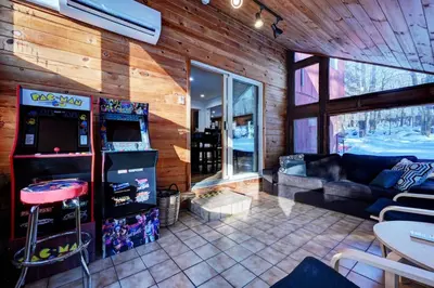 a living room with a game machine in a room at Cozy mountain house with beach access and firepit in Lake Harmony