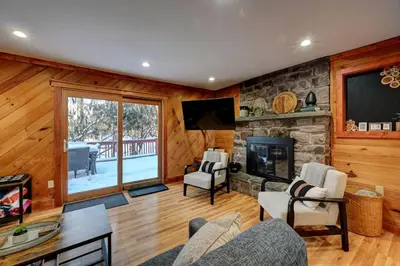 a living room with a stone fireplace and a television at Cozy mountain house with beach access and firepit in Lake Harmony
