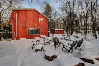 a snow covered yard with chairs and a red barn at Cozy mountain house with beach access and firepit in Lake Harmony