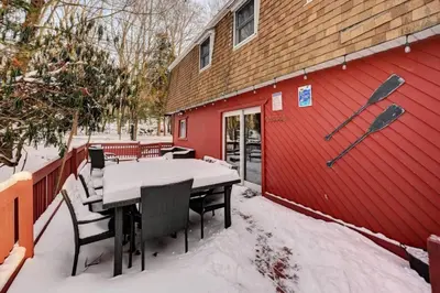 a table and chairs in the snow next to a red building at Cozy mountain house with beach access and firepit in Lake Harmony