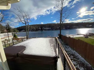 a snow covered deck with a view of a lake at Lakefront home with kayaks fire pit hot tub and walk to restaurants and bars in Lake Harmony