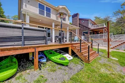 a home with a deck with a kayak parked under it at Lakefront home with kayaks fire pit hot tub and walk to restaurants and bars in Lake Harmony