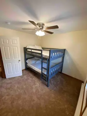 a room with two bunk beds and a ceiling fan at Lakefront home with kayaks fire pit hot tub and walk to restaurants and bars in Lake Harmony