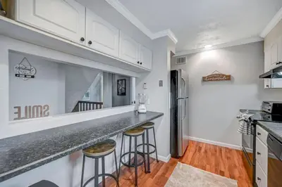 a kitchen with white cabinets and bar stools at Pocono Chalet Towamensing with Hot Tub Lake and Pool in Albrightsville