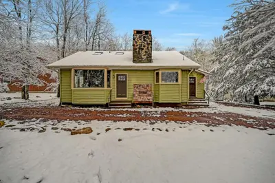 a small yellow house with a chimney in the snow at Lake harmony estates beach and lake access in Lake Harmony