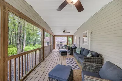 a porch with a couch and a ceiling fan at cozy home in arrowhead lake with huge screened in porch beach and lake and playground in Arrowhead Lake