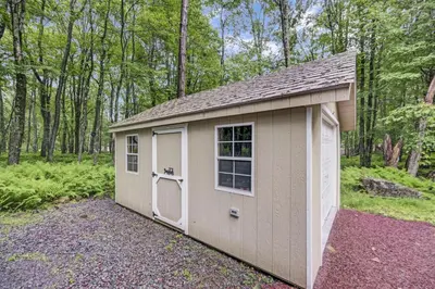 a small shed with a door and a window at cozy home in arrowhead lake with huge screened in porch beach and lake and playground in Arrowhead Lake