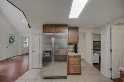 a kitchen with a stainless steel refrigerator and wooden cabinets at cozy home in arrowhead lake with huge screened in porch beach and lake and playground in Arrowhead Lake