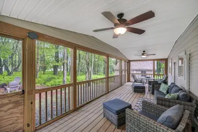 a screened porch with couches and a ceiling fan at cozy home in arrowhead lake with huge screened in porch beach and lake and playground in Arrowhead Lake
