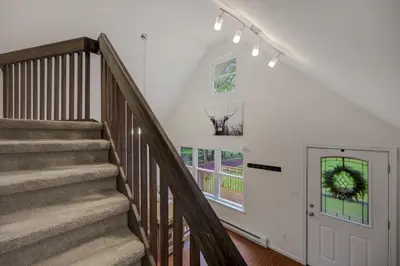 a staircase in a home with a white wall at cozy home in arrowhead lake with huge screened in porch beach and lake and playground in Arrowhead Lake