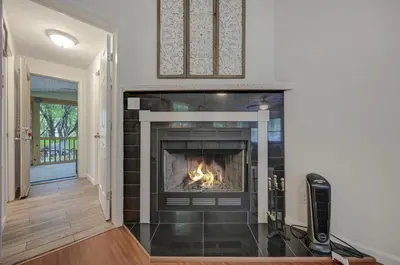 a fireplace in a living room with a fire in it at cozy home in arrowhead lake with huge screened in porch beach and lake and playground in Arrowhead Lake