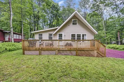 a home with a large wooden deck in the yard at cozy home in arrowhead lake with huge screened in porch beach and lake and playground in Arrowhead Lake