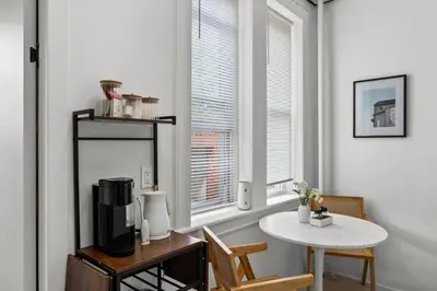 a white room with a table and a window at Modern Studio - Parking Available - 15 min NYC in Jersey City