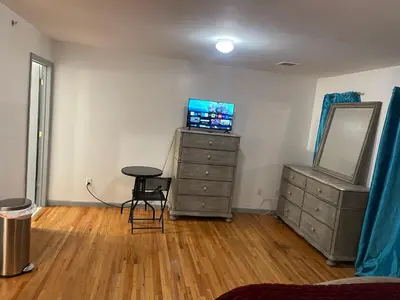 a room with a dresser with a mirror and a television at Peculiar 153 in Newark