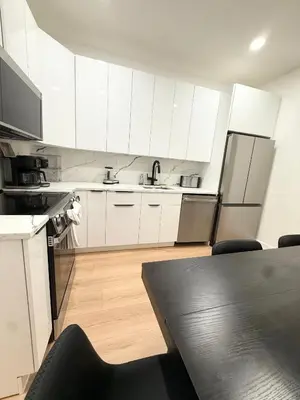 a kitchen with white cabinets and a table with chairs at The View - Direct Bus Time Square NYC Breakfast Included - A in Jersey City