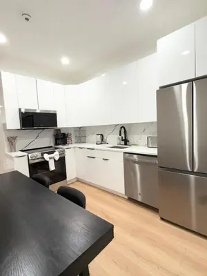 a kitchen with white cabinets and a stainless steel refrigerator at The View - Direct Bus Time Square NYC Breakfast Included - A in Jersey City