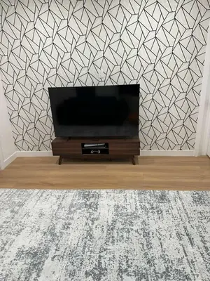 a flat screen tv in a living room with a geometric wallpaper at The View - Direct Bus Time Square NYC Breakfast Included - C in Jersey City