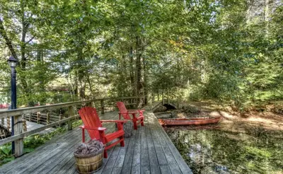two red chairs sitting on a wooden deck at Cozy Cottage Rental with Small Private Pond in Canadensis, Pennsylvania in Canadensis