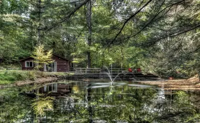 a pond in front of a log cabin at Cozy Cottage Rental with Small Private Pond in Canadensis, Pennsylvania in Canadensis