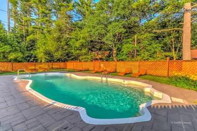 a swimming pool in a backyard with an orange fence at Cozy and Secluded Cabin with a Fireplace in the Poconos Mountains of Pennsylvania in Canadensis