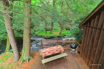 a wooden bench sitting on a deck next to a grill at Traditional Wooden Cabin Rental in the Poconos, Pennsylvania in Canadensis