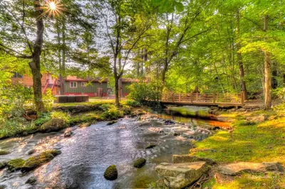 a creek with a bridge and a house in the background at Traditional Wooden Cabin Rental in the Poconos, Pennsylvania in Canadensis