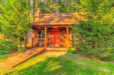 a wooden cabin with a red door in the woods at Traditional Wooden Cabin Rental in the Poconos, Pennsylvania in Canadensis