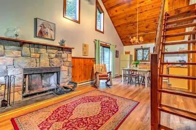 a living room with a stone fireplace and a table at Traditional Wooden Cabin Rental in the Poconos, Pennsylvania in Canadensis