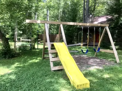 a wooden swing set with a yellow slide at Private Cabin Rental with Wood-Burning Fireplace in Canadensis, Pennsylvania in Canadensis