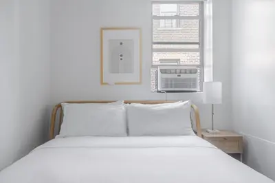 a bedroom with a bed with white sheets and a window at Blueground Bloomingdale fitness center nr Central Park NYC-1869 in New York