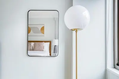 a mirror on a wall next to a floor lamp at Blueground Manhattan Valley fitness nr Central Park NYC-1101 in New York