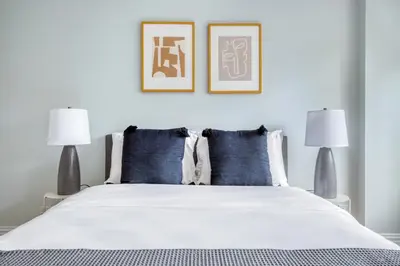a bedroom with a bed with blue pillows and two lamps at Blueground Manhattan Valley fitness nr Central Park NYC-1101 in New York