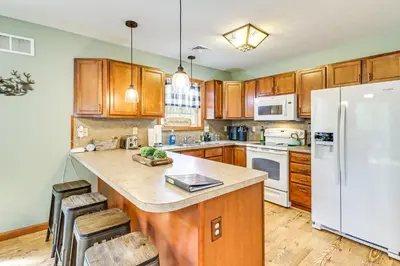 a kitchen with wooden cabinets and a white refrigerator at Game Room and Lake Access Albrightsville Escape in Albrightsville