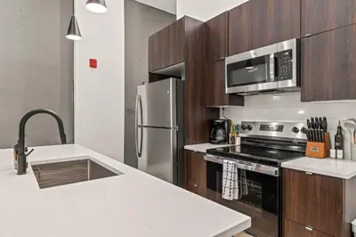 a kitchen with wooden cabinets and a stainless steel refrigerator at SLEEP 8 Outdoor Patio-Old City- 2 NEW Townhouses in Philadelphia