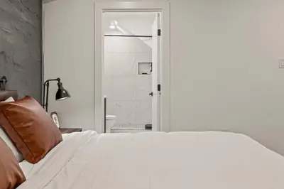 a bedroom with a white bed and a bathroom at SLEEP 8 Outdoor Patio-Old City- 2 NEW Townhouses in Philadelphia