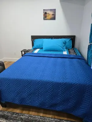 a blue bed with blue pillows on top of it at Tkc Villa in Newark