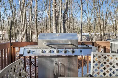 a grill on a deck with trees in the background at Pocono Home Hot tub Camelback Lake Pool in Albrightsville