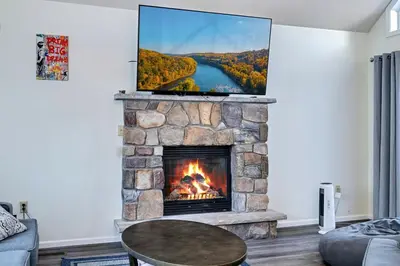 a living room with a fireplace with a tv above it at Pocono Home Hot tub Camelback Lake Pool in Albrightsville