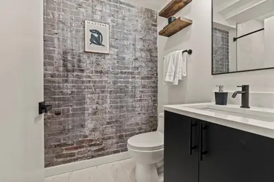 a bathroom with a white toilet and a brick wall at New Townhouse Sleep 4 Old City Walk to Everything! in Philadelphia