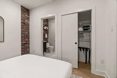a bedroom with a white bed and a brick wall at In The Center of Old City Philly- Walker Paradise! in Philadelphia