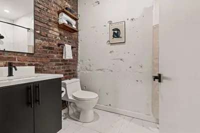 a bathroom with a white toilet and a brick wall at In The Center of Old City Philly- Walker Paradise! in Philadelphia